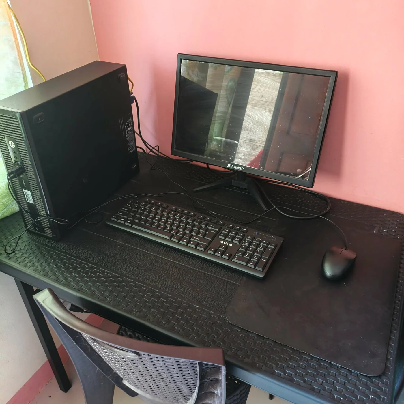 A closer look at the same desktop setup against the pink wall